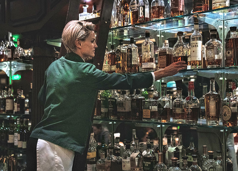 Bartender retrieving liquor from a shelf